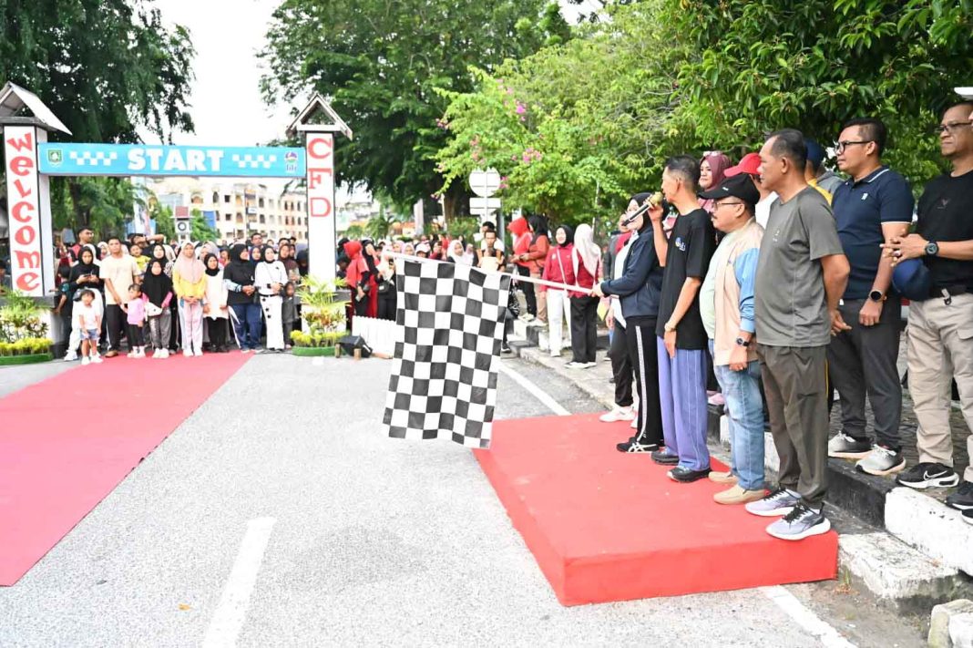 Teks foto: Kepala Kejaksaan Negeri Bengkalis, Nadda Lubis, mengibarkan bendera start tanda dimulainya Car Free Day dan Jalan Santai dalam rangka HUT ke-24 PT. Bumi Laksamana Jaya (Perseroda) Bengkalis Tahun 2025.